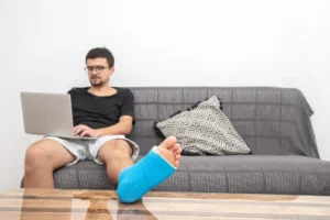 Hombre teletrabajando con el pie escayolado
